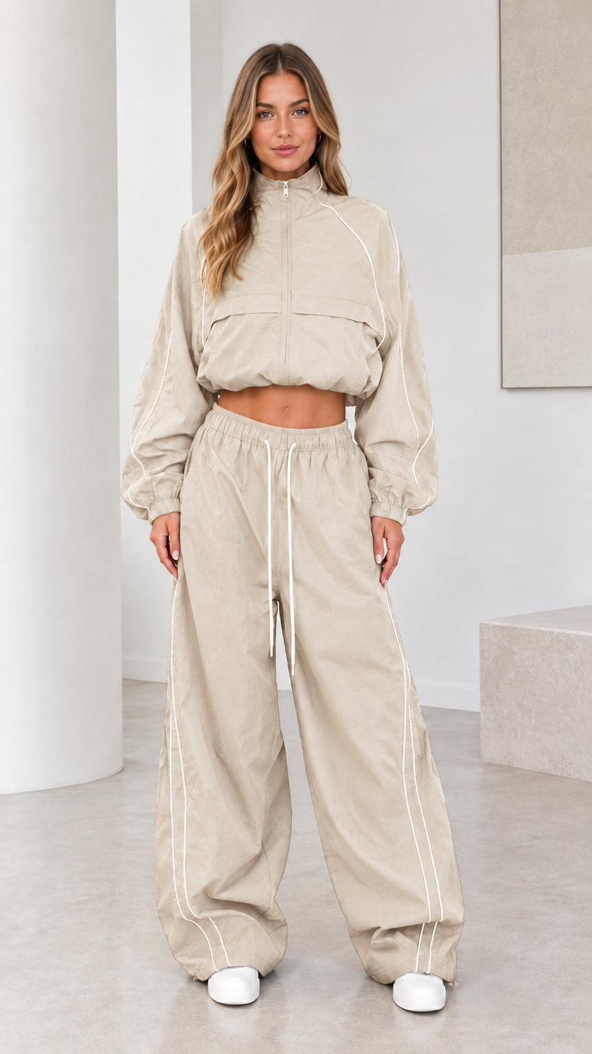 Front view of model wearing beige cropped windbreaker and parachute pants set