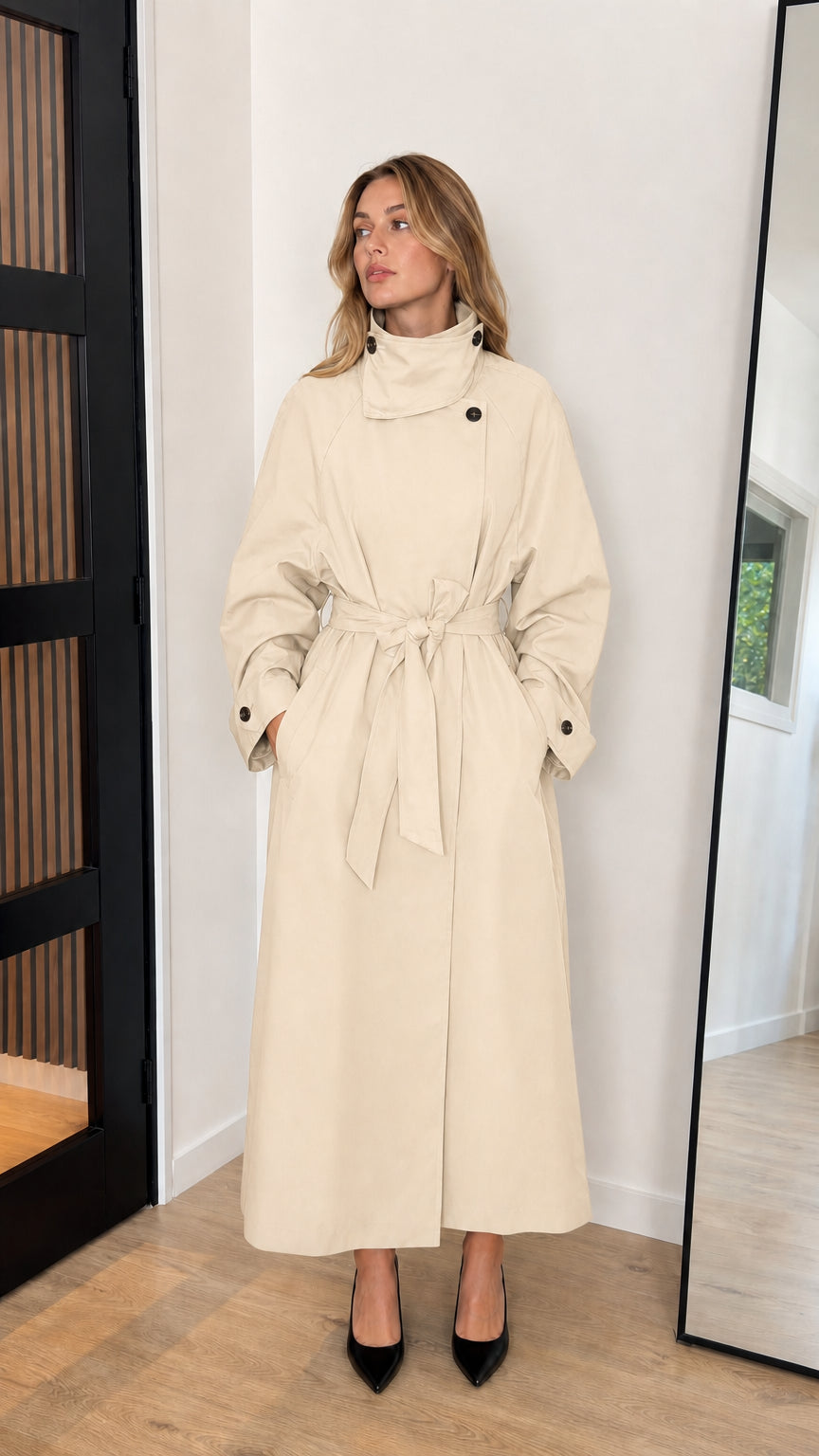 Front view of model wearing a cream light beige high neck belted longline trench coat