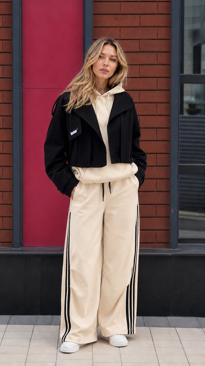 Model wearing beige hoodie and wide leg sweatpants set with cropped black jacket