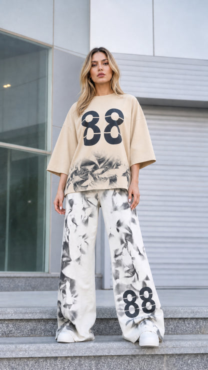 Front view of woman wearing beige graphic tee and matching printed wide-leg pants