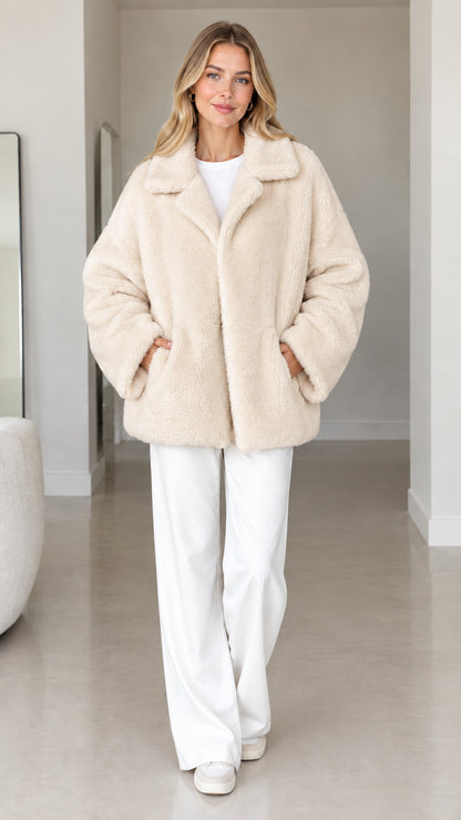 Front view of model wearing cream plush faux fur lapel coat
