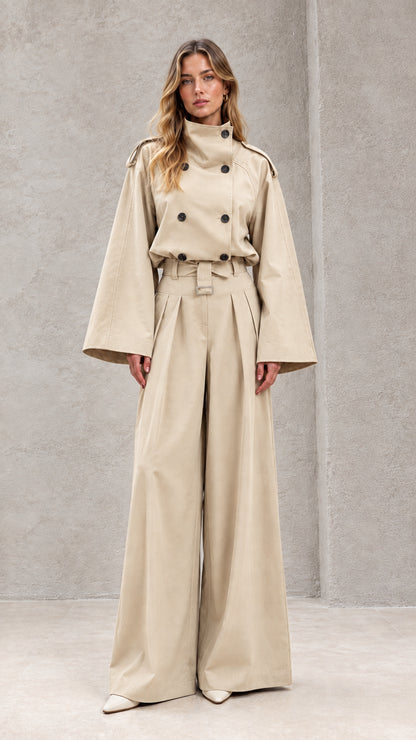 Front full-length view of model in sand beige double-breasted wide-leg trench jumpsuit